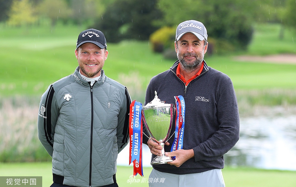 布兰德在果岭上振臂高呼，肆意庆祝胜利，背景中的观众为他热烈鼓掌。