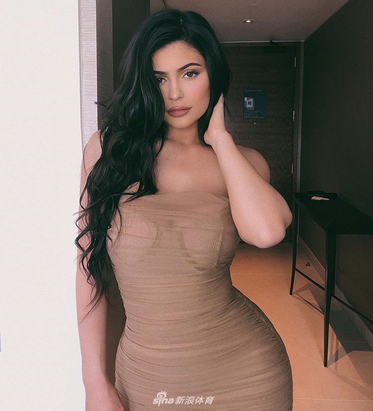 凯莉詹娜正在专注地观察球路，侧颜精致，身上的香奈儿套装在球场绿地的映衬下显得格外优雅时髦。