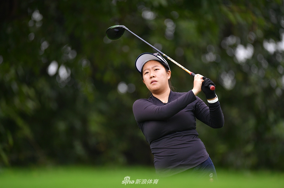 石昱莉单膝跪地专注看线，手指轻触果岭感受坡度，专业姿态尽显无遗