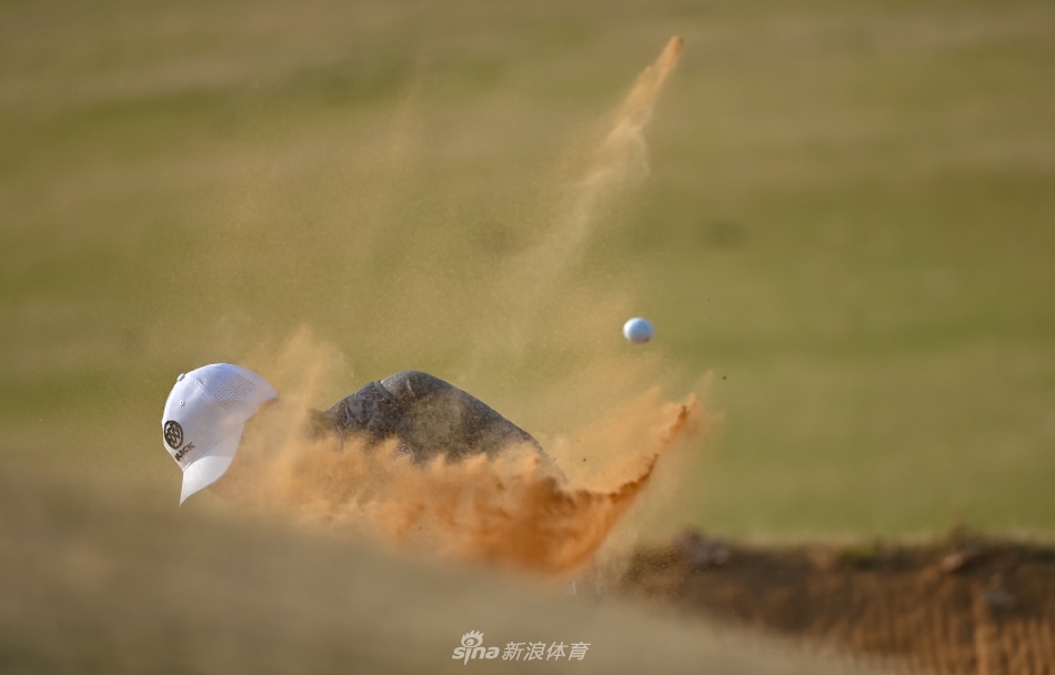 年轻小将凝神屏息,沙坑中精准救球,沙粒飞扬间尽显沉稳果敢