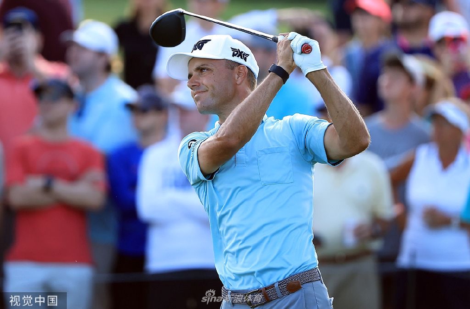 科克高举冠军奖杯向观众致意，身后是碧绿的果岭与欢呼的人群，阳光洒满胜利的时刻