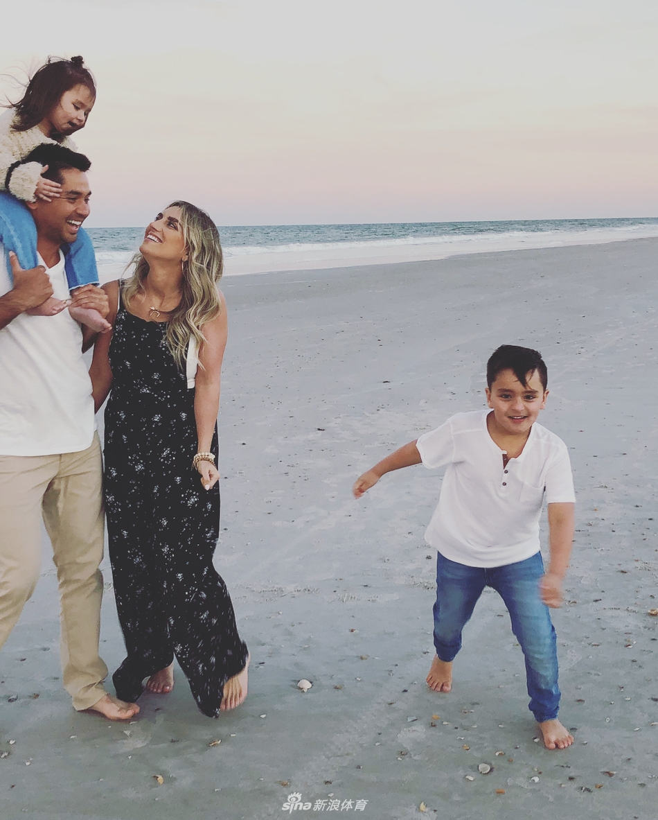 一家四口在草地上嬉戏，小儿子达什兴奋地跳跃起来，仿佛要触摸天空。