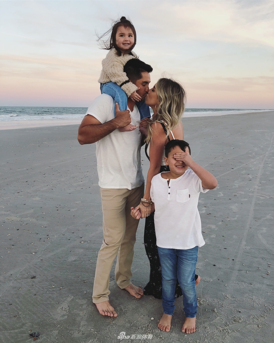 简森·戴伊将儿子高高举起，父子二人开怀大笑，阳光洒在他们身上格外温馨。