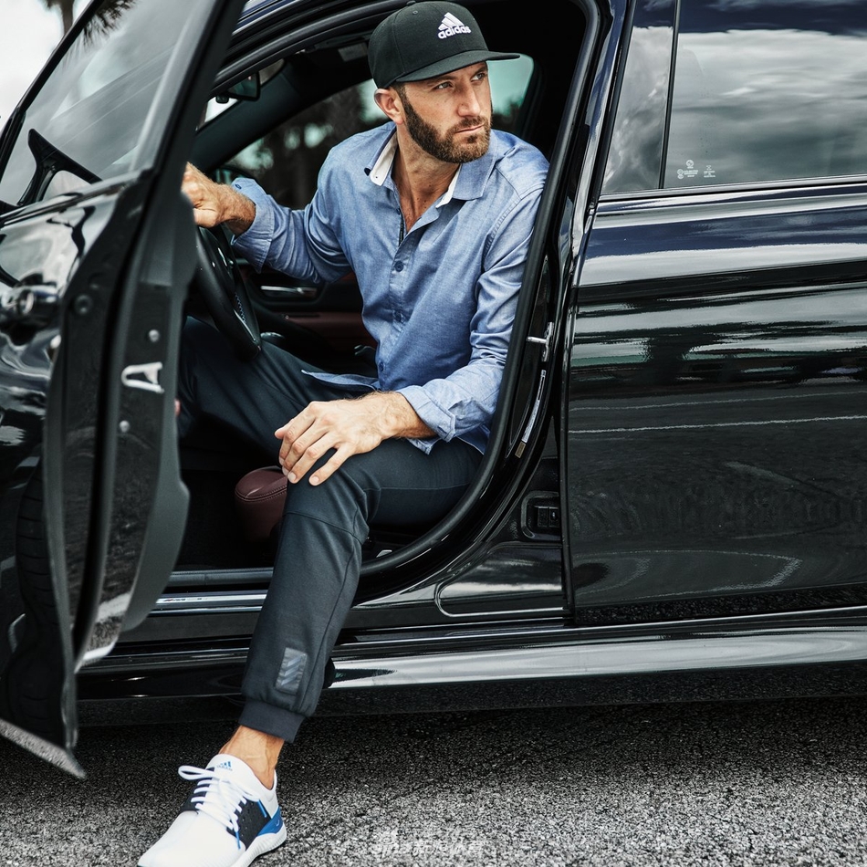 塞尔希奥·加西亚倚靠车身,双臂轻松交叠,嘴角扬起一抹自信弧度,午后的阳光为他周身镀上一层金色光晕