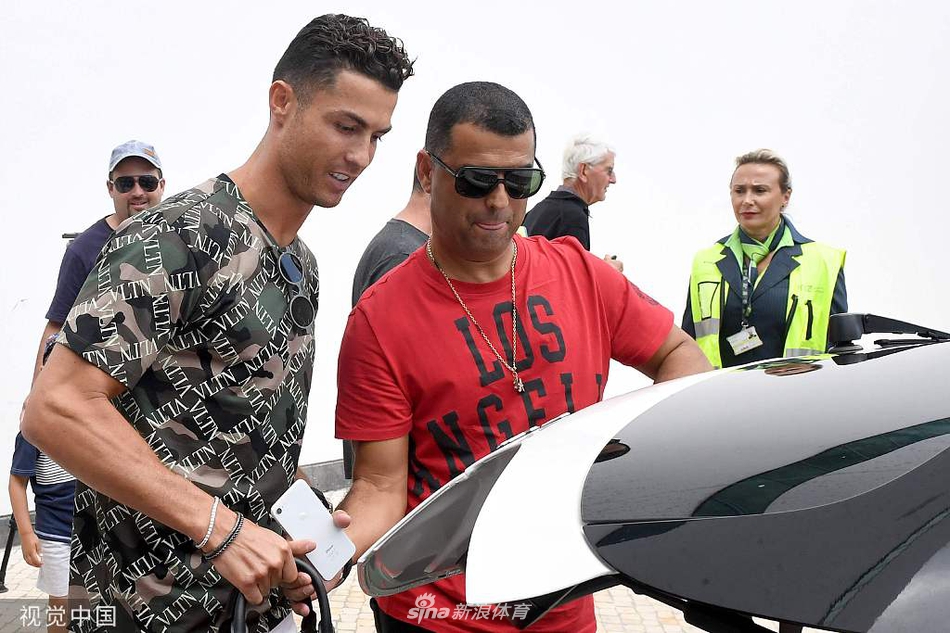 C罗被一群热情的孩童球迷包围，他弯下腰认真地为小家伙们签名，乔治娜在旁边露出宠爱的微笑，背景的绿树与白墙衬托出这幕跨越年龄的足球情缘。