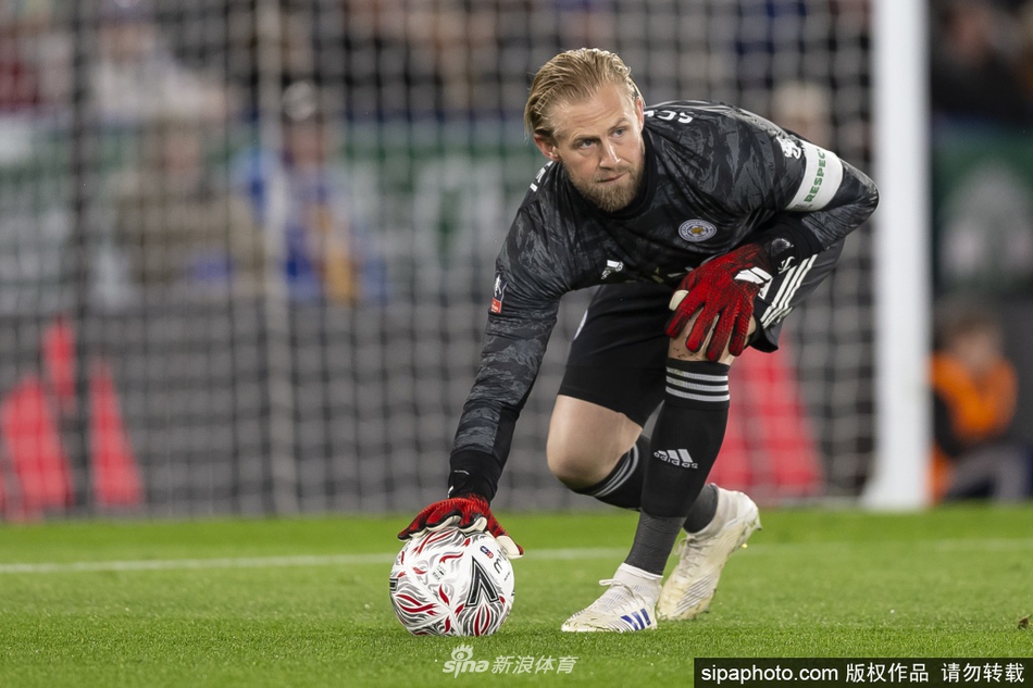 小舒梅切尔身穿深色训练服，面带微笑，双手抱在胸前，显得从容自信，身后的训练场沐浴在柔和的阳光下。