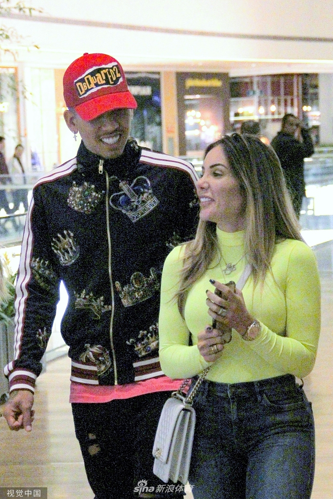 菲尔米诺手拿购物袋，与女子边走边聊，氛围轻松