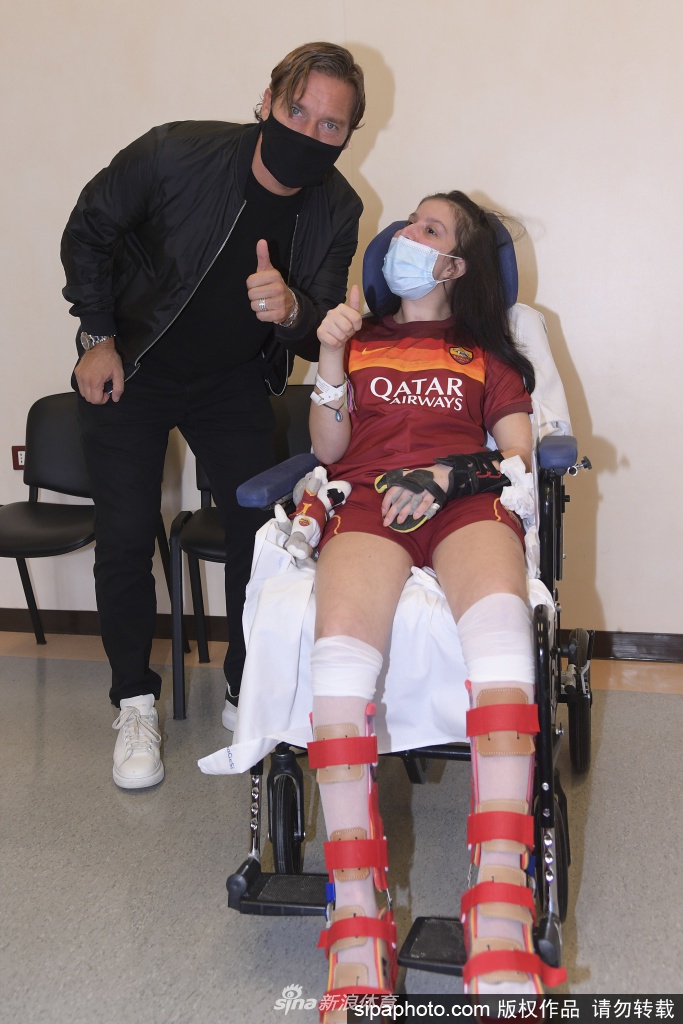 身穿罗马球衣的伊莱妮娅静静地躺在病床上，虽然身体尚未康复，但当托蒂来到身边时，她的眼中闪烁着光芒，一只手轻轻抬起，仿佛想要触碰近在咫尺的偶像，这一刻，语言已是多余。