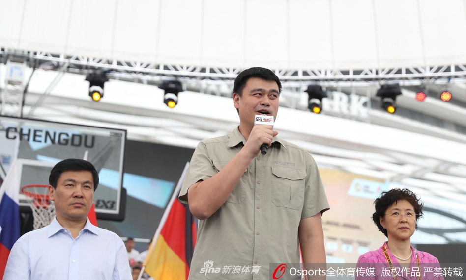 姚明坐在看台上专注地观看揭幕战，他双手搭在膝盖上，神情严肃而投入，仿佛比场上的球员更加紧张。