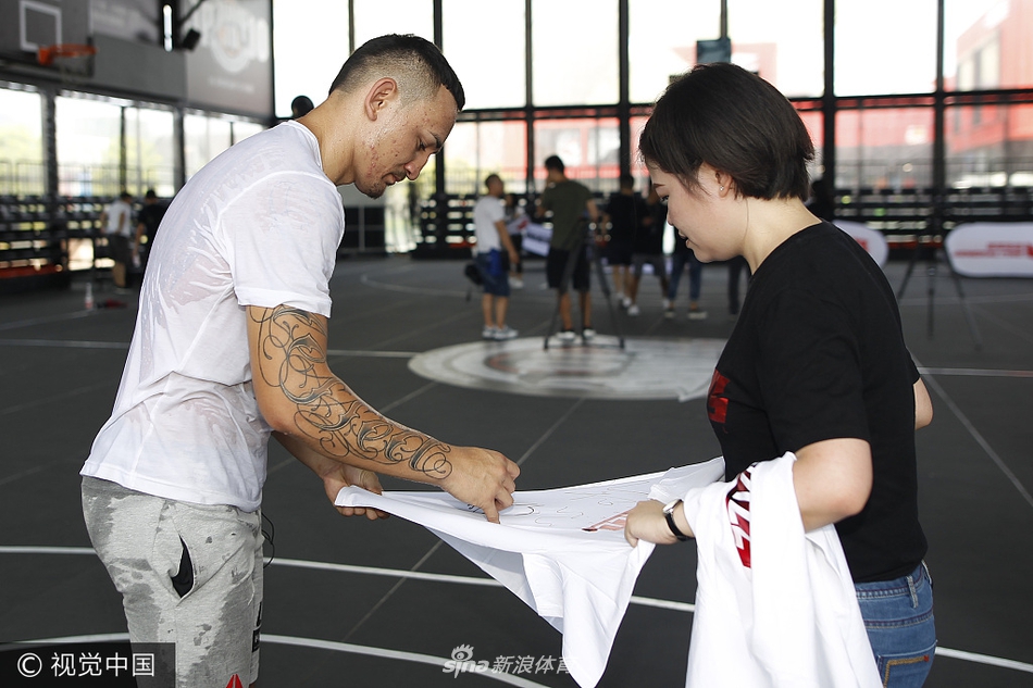 UFC名将李景亮在篮球场上持球进攻，面对防守球员，他眼神专注而犀利，尽管是跨界到篮球场，他依然保持着在八角笼中特有的沉稳与狠劲，准备完成一次上篮。