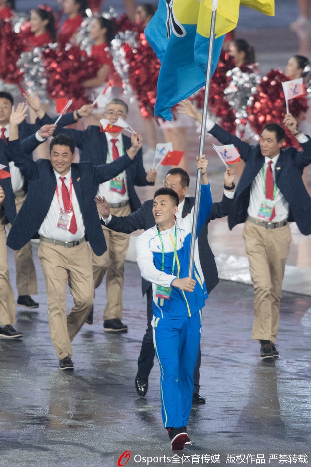 旗手郭艾伦目光坚毅，他的身后是璀璨的天津全运会主火炬，象征着薪火相传的体育精神。