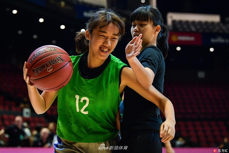 身穿红色球衣的小球员在职业赛场上毫不怯场,他正眼神坚毅地运球突破,对面的大哥哥则面带微笑认真防守,传承在这一刻悄然发生。