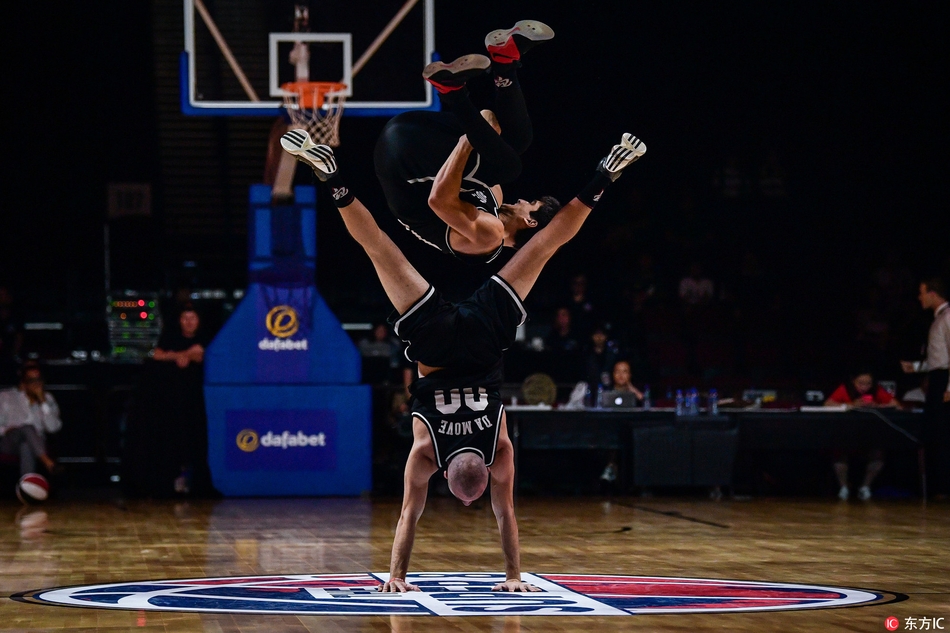 表演者身体舒展,眼神专注,篮球在他胯下划出一道优美的弧线,精准地飞向另一只手的掌控范围,充满了动感与韵律美。