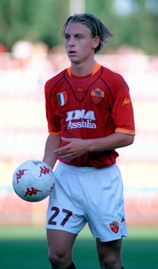 德罗西俯身亲吻罗马队徽，这一吻深情而专注，仿佛在与胸口的狼图腾进行一场无声的灵魂对话