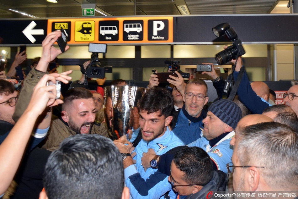 手捧鲜花的拉齐奥球员在安保人员的陪同下穿越狂热的人群，球迷们伸出无数双手臂，只为能更近距离地触摸到他们的英雄，分享这份来之不易的冠军荣耀。