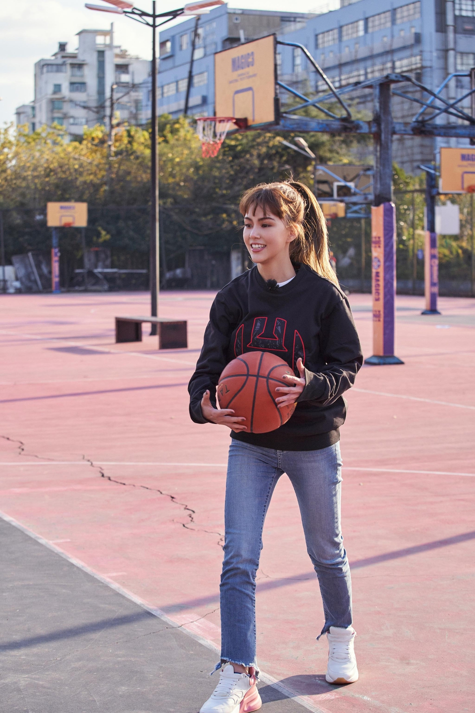 篮筐下，昆凌高高跃起，高举右手准备投篮，黑色的卫衣衣角随动作扬起，高马尾在空中划出一道充满力量的弧线。