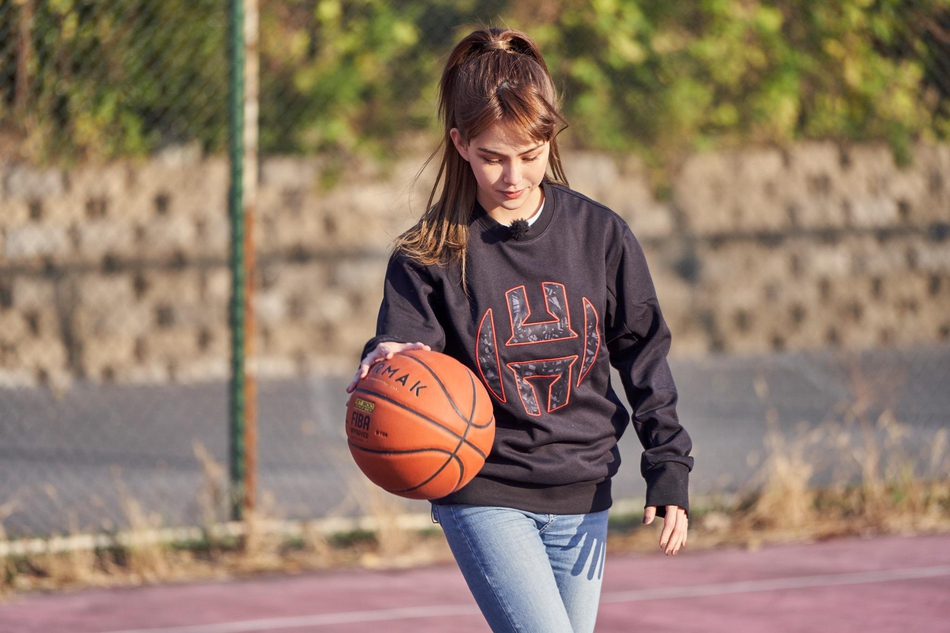 昆凌在无对抗的情况下轻松起跳，手腕轻柔地将篮球拨出，动作舒展优美，篮球在空中旋转着飞向篮筐，姿势与周杰伦如出一辙。