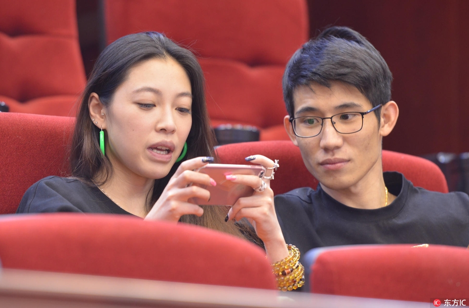 一位戴着黑框眼镜的温婉女球迷，在绿茵背景下露出羞涩而灿烂的笑容，仿佛进球的消息让她既惊喜又甜蜜。