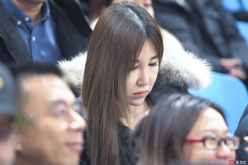 戴着一副时尚眼镜的知性美女，在人群中微微一笑，她不仅在看球，更像是在欣赏一场冬日的篮球盛宴，举手投足间尽显优雅。