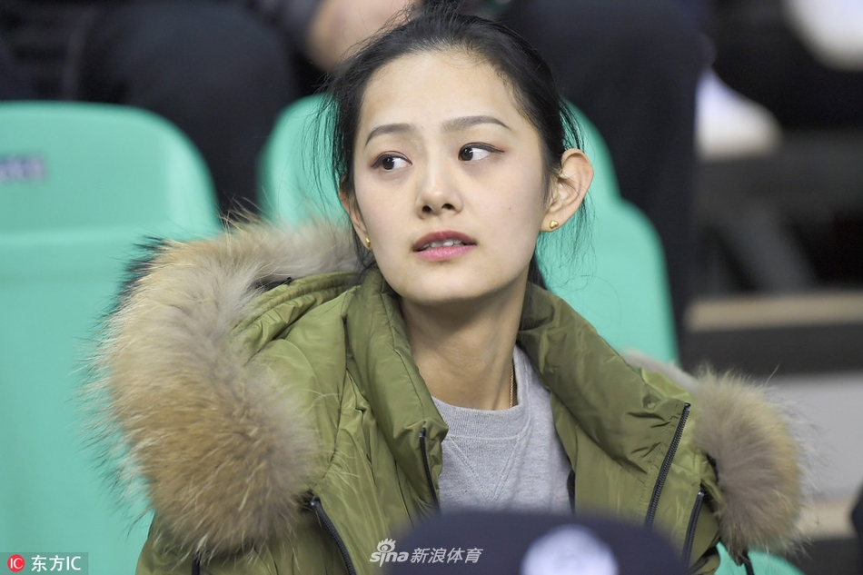 看台上一名穿着时尚的短发女孩正用手机记录赛场瞬间，她身后的球迷们表情各异，整个看台充满了热烈的季后赛氛围。