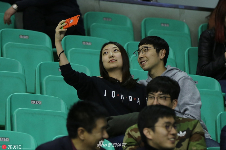 几名年轻的女球迷凑在一起对着镜头比出胜利的手势，她们脸上贴着主队的贴纸，青春洋溢的气息扑面而来。