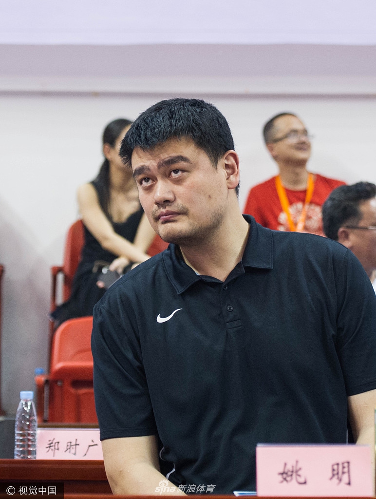 怀集体育馆内灯光璀璨，热情的观众们挥舞着手中的充气棒，目光一致投向场边正在鼓掌的姚明，现场气氛热烈非凡，仿佛一个盛大的节日庆典。