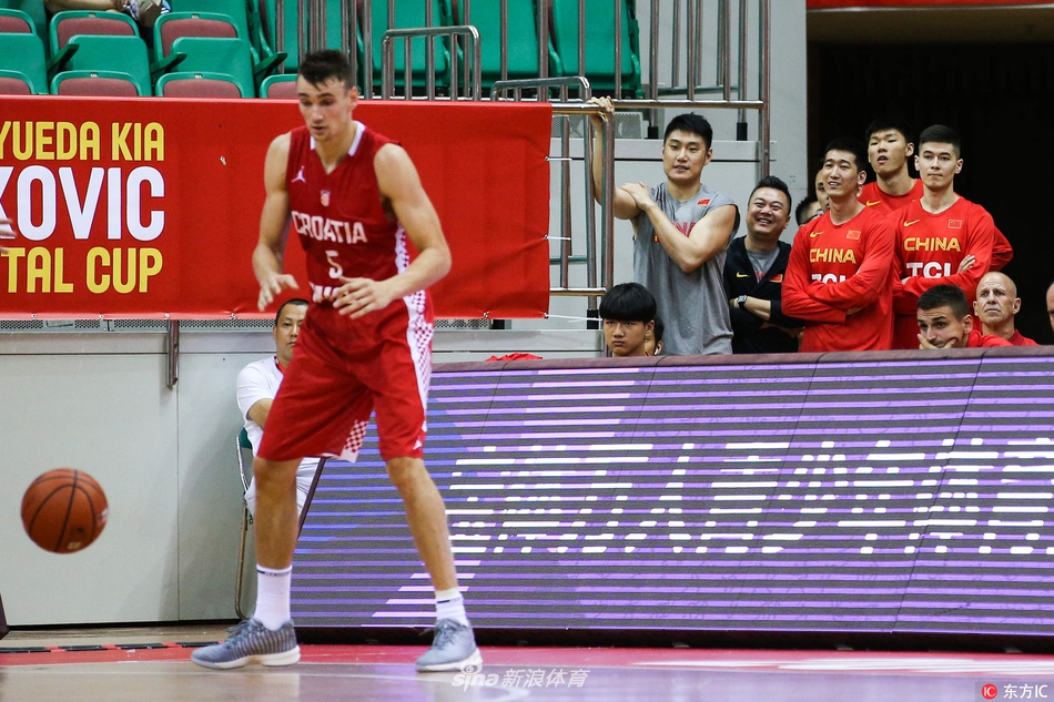 镜头拉近，中国男篮的一位球员眼神专注，嘴唇微张，似乎完全沉浸在了比赛的节奏里。背景是模糊的看台观众，他的脸上还带着些许属于年轻人的稚气，但在那一刻的凝视中，透露出的是超越年龄的沉稳。仿佛正在心中默默模拟，如果换做是自己，该如何应对眼前这激烈的欧洲对抗。