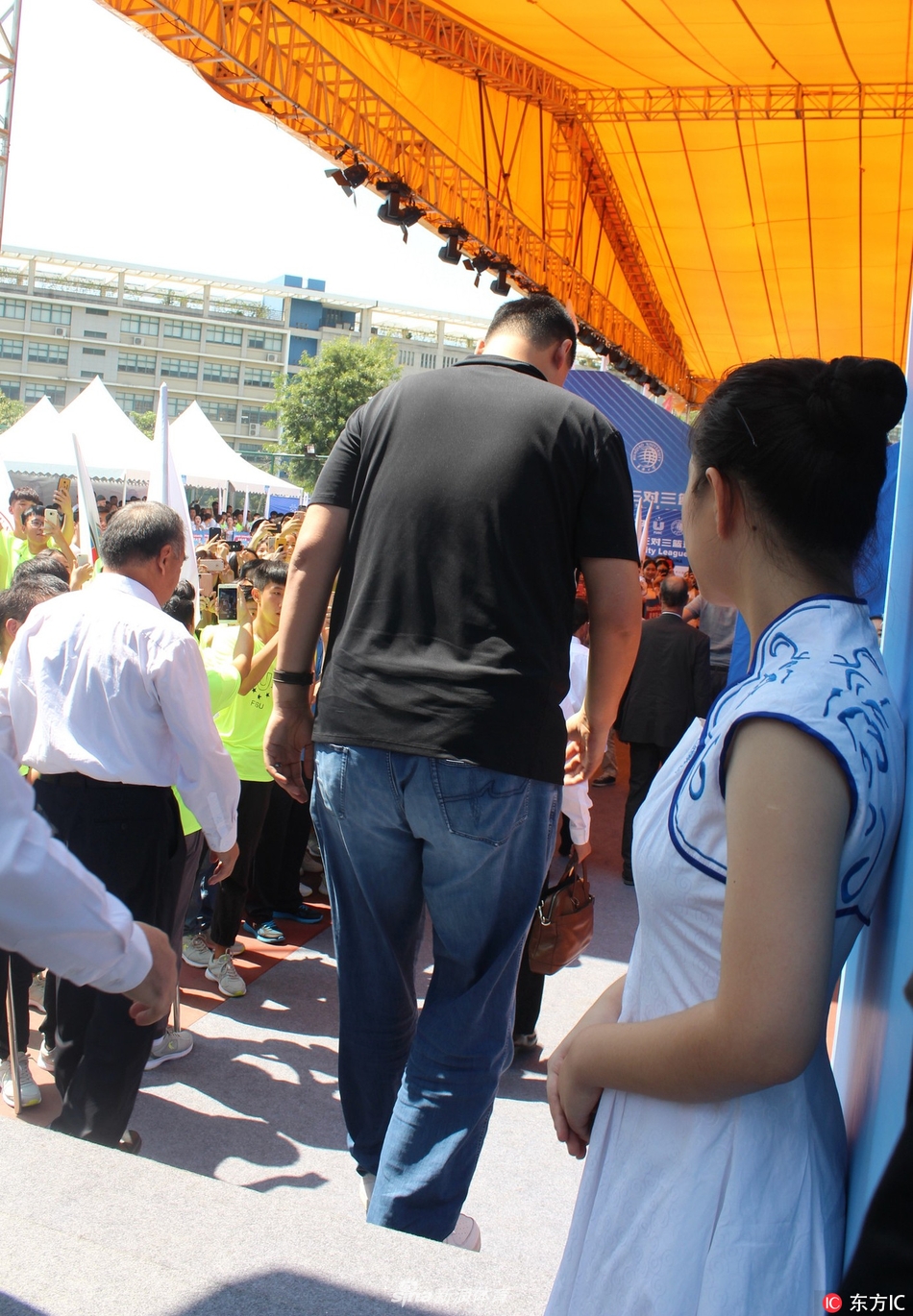 姚明端坐在看台上专注观赛，周围是热情的大学生们，他的目光紧紧跟随着球场上的攻防转换，仿佛也在回忆自己曾经在赛场上的峥嵘岁月。