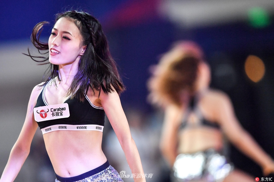 身着统一亮黄色短裙的拉拉队员们排成整齐的队列，在动感的音乐节奏中做出整齐划一的踢腿动作，她们的身影与地板上的倒影交相辉映，构成一幅充满活力的画面