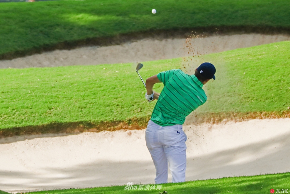 东湖球场全景鸟瞰，绿意盎然的球道与湛蓝的水障碍交错，球员与观众点缀其间，宛如一幅生动的运动画卷