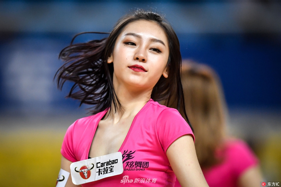 特写镜头中,这位啦啦宝贝的笑容极具穿透力,仿佛能驱散一切疲惫。她手中的花球如同被施了魔法,在聚光灯下闪烁着迷人的光彩,与她眼中的星光交相辉映。