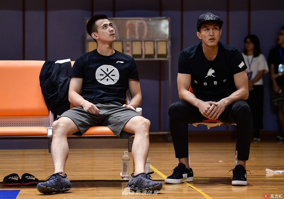 郭艾伦神情专注地坐在场边，身着便装观看着场内激烈的比赛，眼神中透露出对赛场的渴望