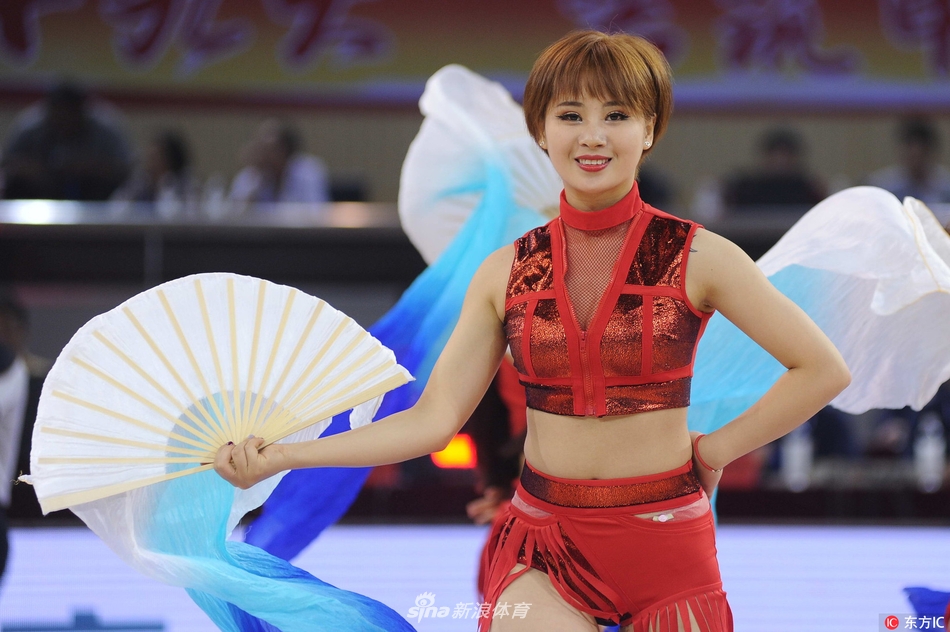 啦啦宝贝正在表演高难度的舞蹈动作，她身体后仰展现出极佳的柔韧性，手中的花球如同流星般在灯光下留下璀璨的光影，现场气氛被推向高潮