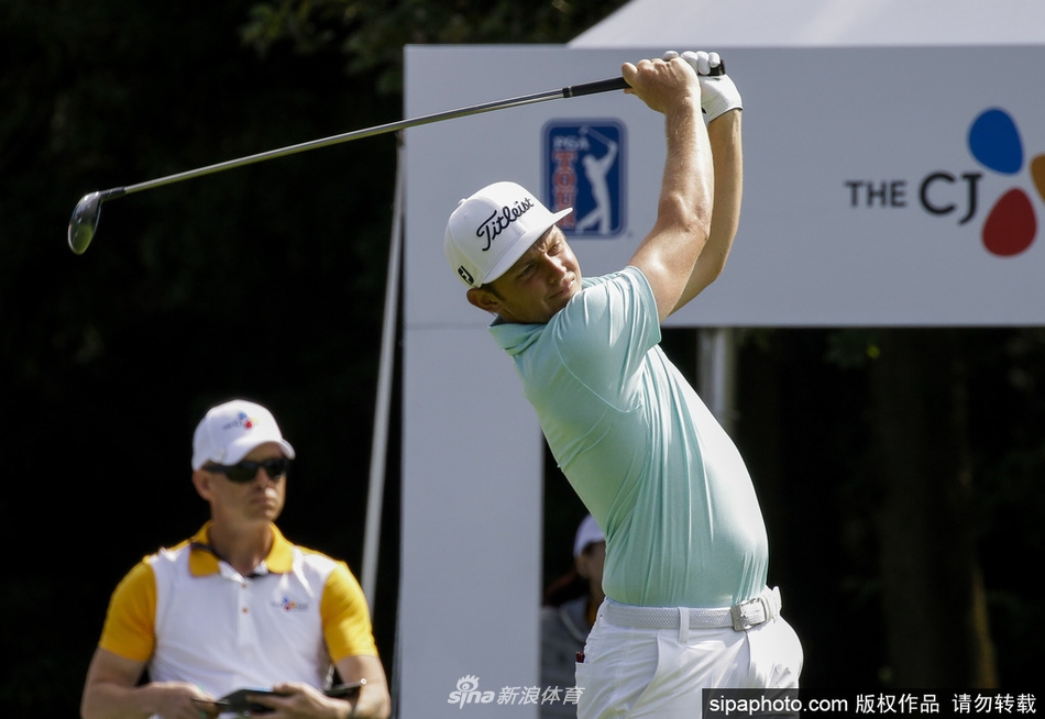 球员在果岭上俯身仔细查看推杆线路，起伏的果岭与远处山景构成独特赛场画卷。