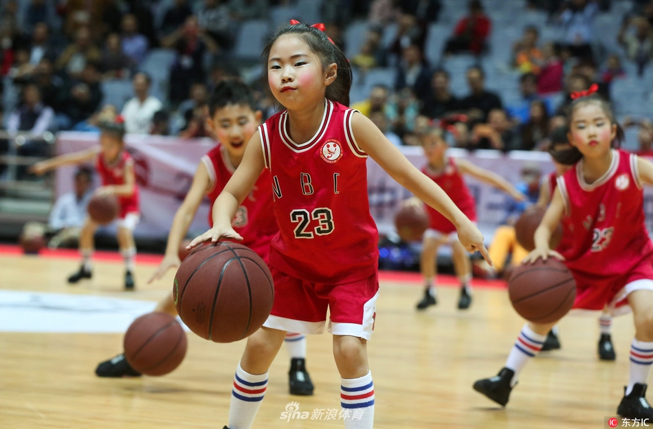 镜头捕捉到一位小球员高高跃起投篮的瞬间，篮球在空中划过一道优美的弧线，他的眼神紧紧追随，整个球馆的灯光仿佛都聚焦在他身上。