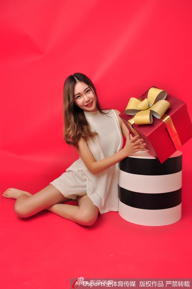 思凡手捧一个红色的圣诞礼盒，笑容比身后的圣诞树还要灿烂，充满治愈感。