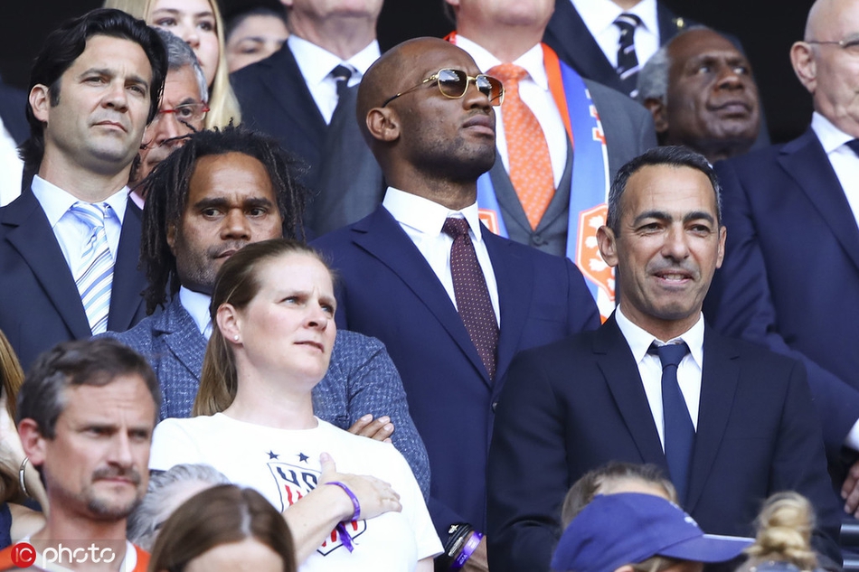 法国天才姆巴佩坐在看台上神情专注，他的目光紧盯着场内奔跑的女足球员，仿佛在从另一个视角解读比赛，对赛场上展现出的战术与意志力深感着迷。