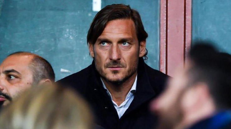 身披罗马战袍的托蒂在场上振臂高呼，阳光下的金发闪耀夺目，定格了他与红狼并肩作战的荣耀瞬间