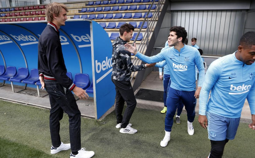 蒂姆手持自己的网球拍，与巴萨训练场上的足球标志物合影，巧妙地将网球与足球元素融为一体