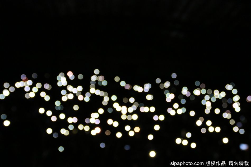 观众们排成一条长龙，正借着手机灯光有序地走向出口，光线在人群中流动，勾勒出一幅互帮互助、文明礼让的画面