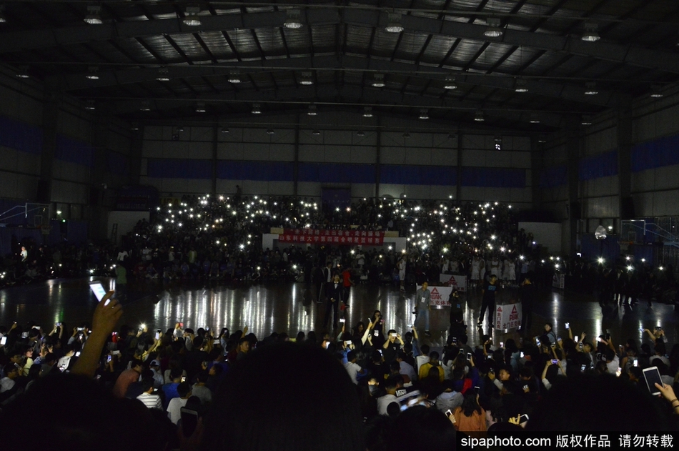 几位学生肩并肩站在一起,同时举起手机,脸上带着灿烂的笑容,手机的光芒照亮了他们的脸庞和身后的黑暗