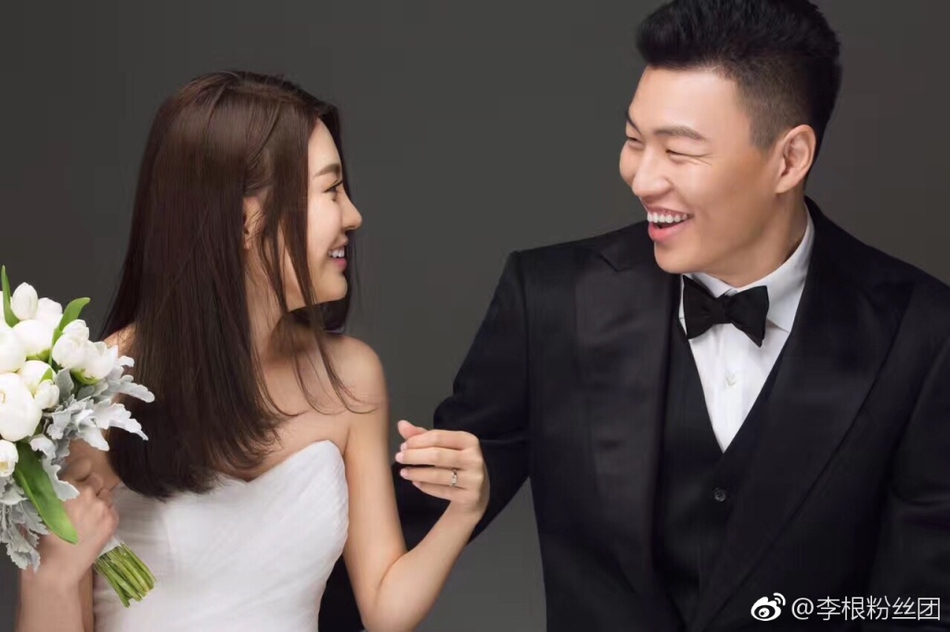 在一片温馨的布置中，李根与妻子轻松互动，背后是红色的国家队球衣，幸福的笑容在他们脸上洋溢，仿佛整个世界都为这份爱而静止。