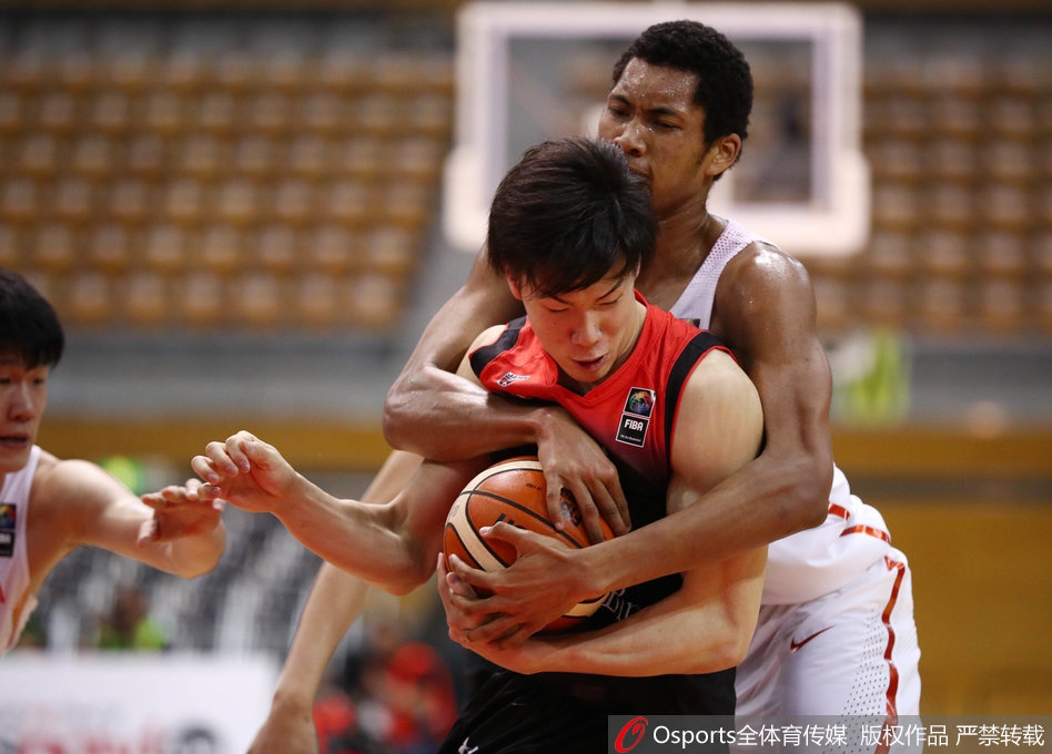 身穿白色球衣的中国国奥队员赵岩昊，在紫色球衣的日本队员严防死守下，依然自信出手，篮球在空中划出优美弧线。