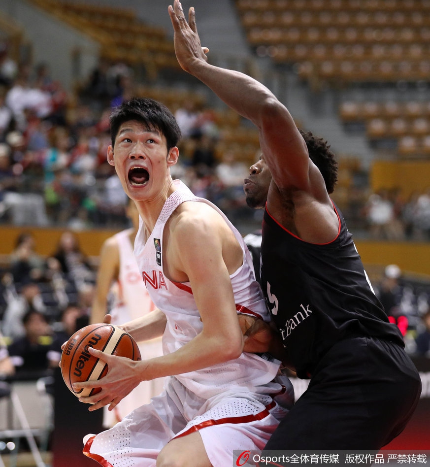 混血球员丘天在篮下高高跃起，利用臂展优势尝试封盖对手的上篮，他的身影在灯光下显得格外充满潜力。