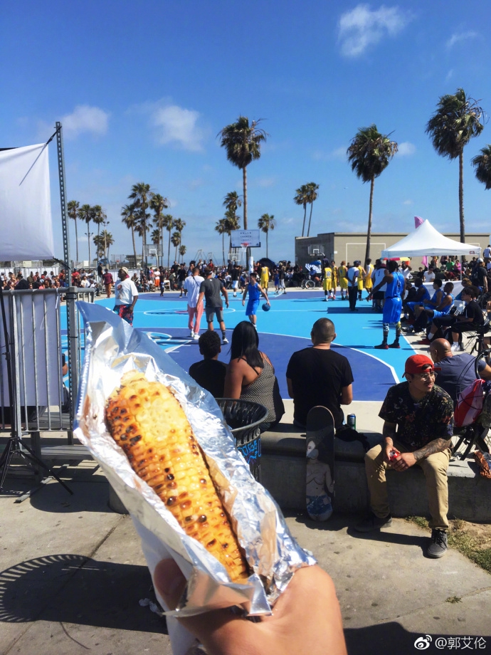 黄昏的海滩边,郭艾伦与一群街头篮球手围在一起,他手里还攥着没吃完的烤苞米,完全融入了这片自由而热烈的篮球氛围中。