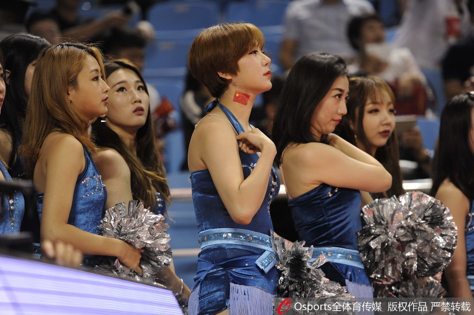 宝贝们身着红白相间的动感队服，侧身凝视镜头，嘴角带着一抹甜美的微笑，修长的身影在球场地板的映衬下格外迷人。