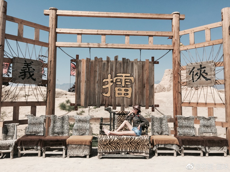 夕阳的余晖洒在许诺身上，她身穿简约的白色上衣，依靠在古朴的土墙边，脸上带着温婉的笑容。光影勾勒出她修长的身形，让这双大长腿显得格外温柔而有故事感。