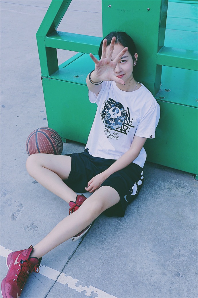 孙夕雨身着白色骑士队T恤,双手叉腰站在街头篮球场边,阳光洒在她身上,甜美的气质中透着一股不服输的劲头。