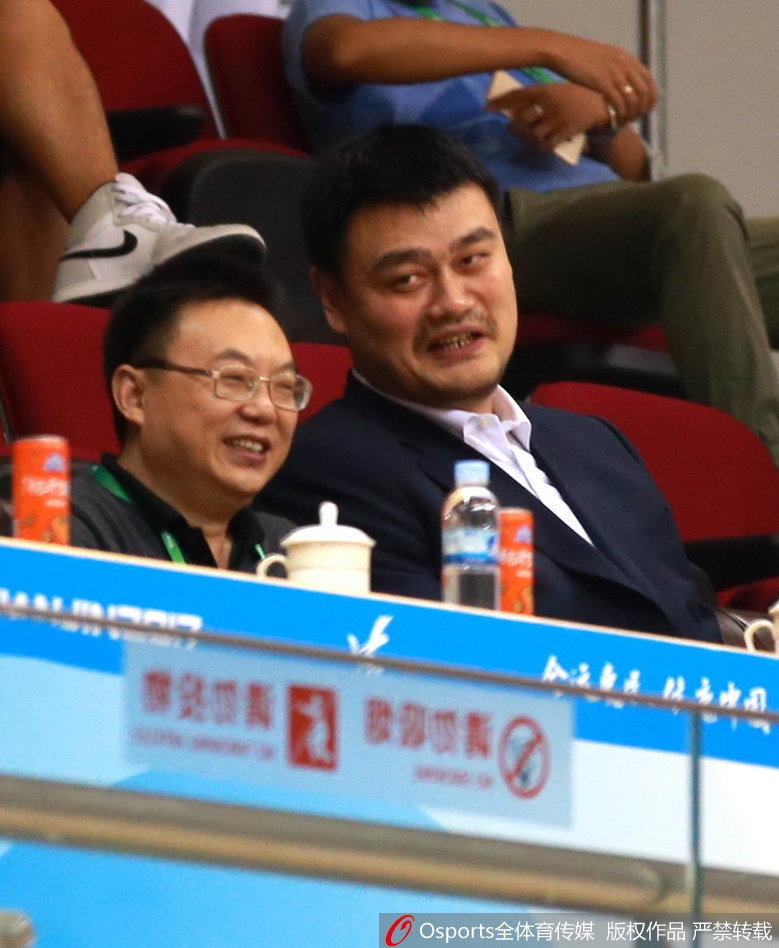 当比赛进入暂停时段，姚明与身旁的友人不经意间的交谈，脸上挂着轻松写意的微笑，这和谐的一幕宛如球场边最亮眼的风景线。
