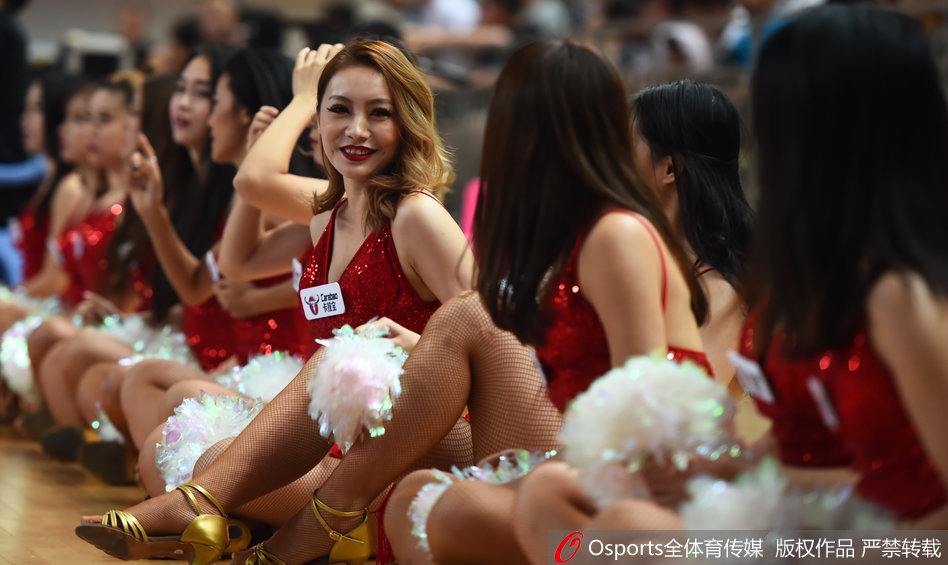 红裙啦啦队领舞者激情绽放,长发飘飘,眼神充满感染力,身后的记分牌映衬着赛场的紧张